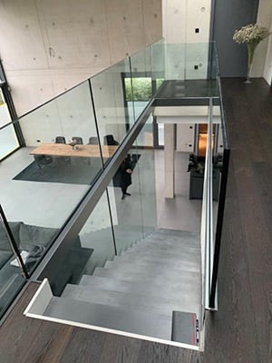 Moderne Glasgeländer-Treppe mit transparenten Glasscheiben und Stahlhandlauf in einem zeitgemäßen Gebäude in Frechen.