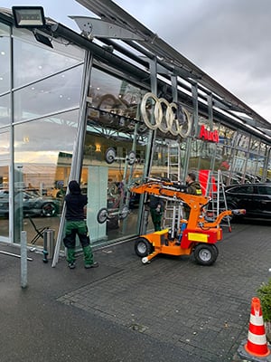 Glaserei-Monteur installiert große Glasscheibe an einem Audi-Autohaus in Frechen mithilfe eines Glassaugers.