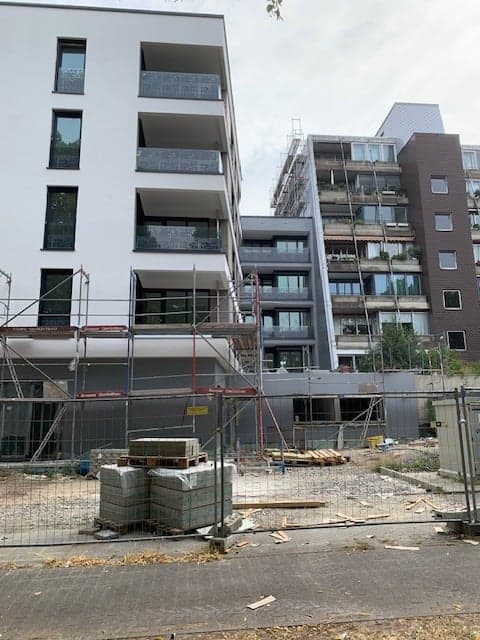 Baustelle mit modernem Mehrfamilienhaus mit Glasbalkongeländern und Gerüst in Frechen.